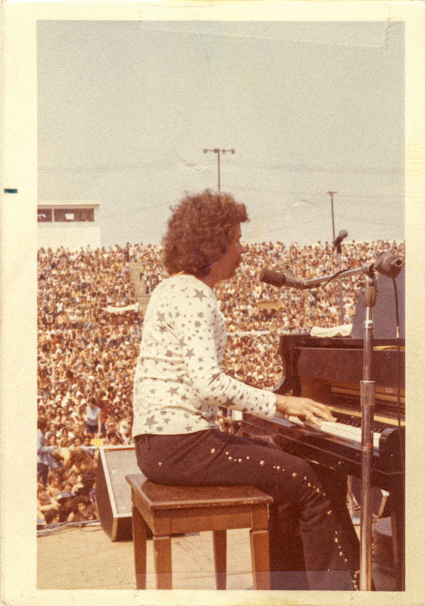 Young Jack Murphy performing at piano before a large outdoor crowd